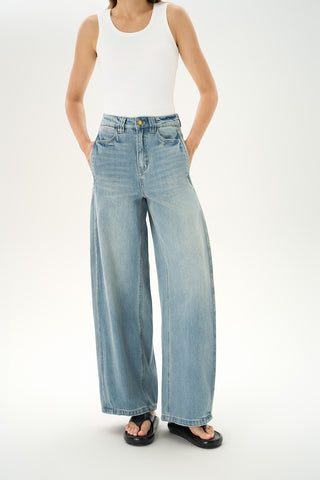 Woman wearing mid-rise light-wash carpenter jeans with paneled construction and wide baggy legs