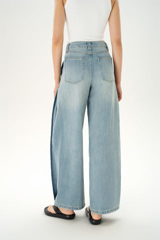 Woman wearing mid-rise light-wash carpenter jeans with paneled construction and wide baggy legs