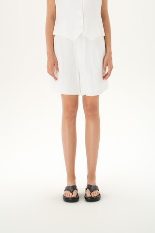 Woman wearing tailored white linen shorts with button closure and pleats