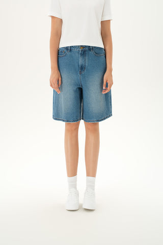 Woman wearing wide-leg denim Bermuda shorts in a mid-rise, medium-light wash