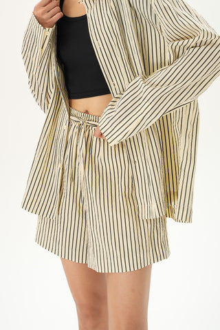 Woman wearing relaxed beige striped drawstring shorts in lightweight crinkled fabric