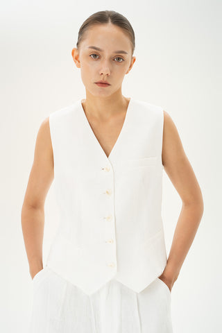 Woman wearing a white tailored linen vest with button-front closure and faux pockets