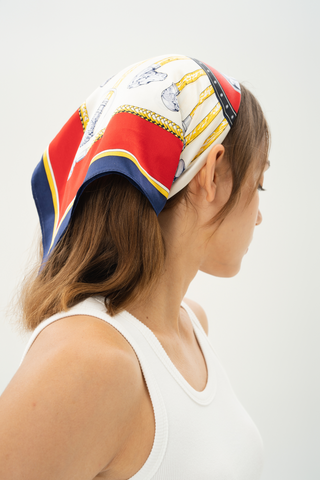 Woman wearing a navy, crimson, and gold silk scarf styled with vintage elegance 