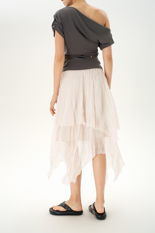 Woman wearing a sheer cream tiered midi skirt with an asymmetrical hem and lightweight layers