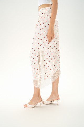 Woman wearing a cream satin midi skirt with red polka dots, featuring a soft asymmetric hem with lace trim