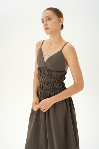 Woman wearing brown taupe midi dress with spaghetti straps, gathered bodice and flowing skirt