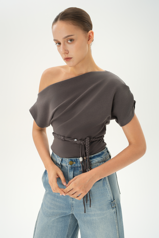 Woman wearing an asymmetric grey off-shoulder top with a braided belt detail