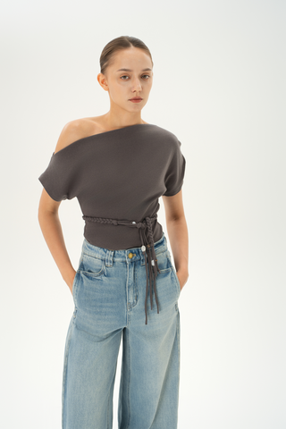 Woman wearing an asymmetric grey off-shoulder top with a braided belt detail