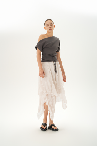 Woman wearing an asymmetric grey off-shoulder top with a braided belt detail