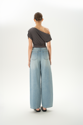 Woman wearing an asymmetric grey off-shoulder top with a braided belt detail